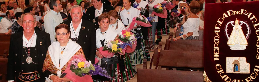 Procesión popular dentro de una iglesia con personas portando ramos de flores.