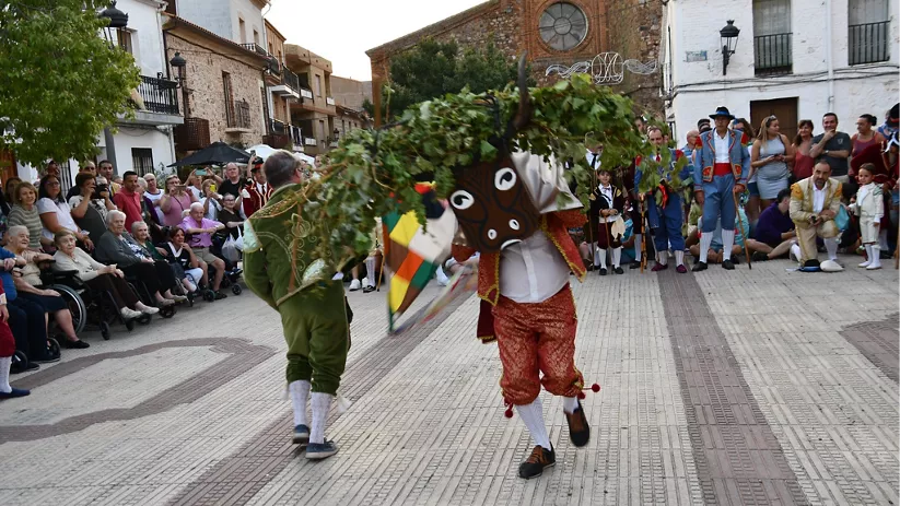 Personaje con máscara y ramas danzando ante el público