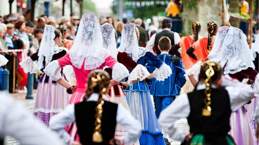 Personas con trajes tradicionales danzando en una calle durante una celebración.