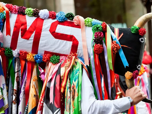 Figura decorada con telas y cuernos durante una celebración popular.