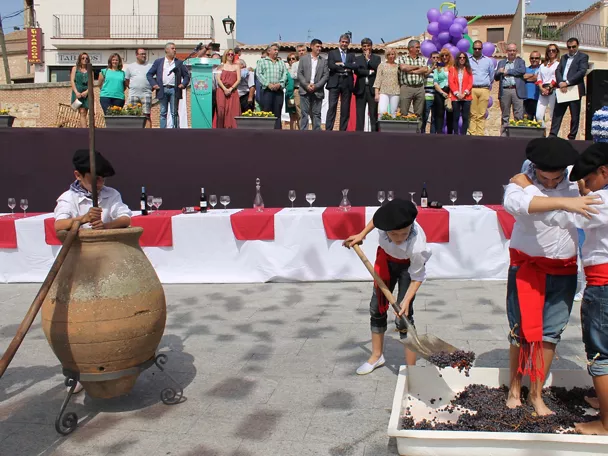 Niños participan en el pisado de uvas durante una celebración popular ante el público.