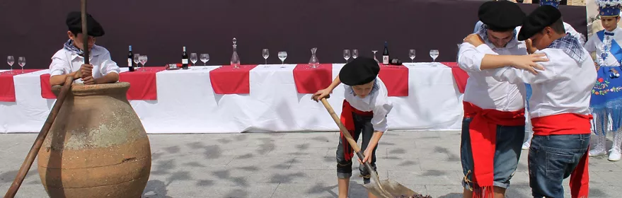 Niños participan en el pisado de uvas durante una celebración popular ante el público.