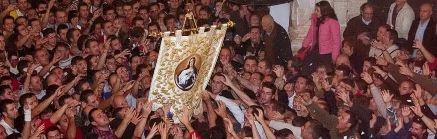 Multitud alzando un estandarte religioso en una plaza abarrotada.