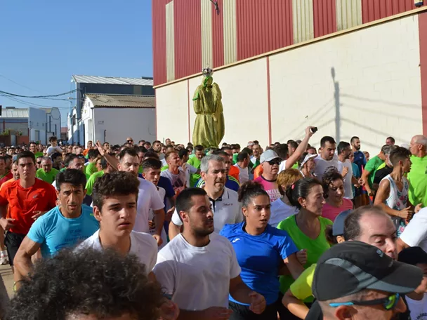 Carrera multitudinaria con participantes avanzando junto a una imagen religiosa.