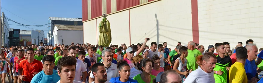Carrera multitudinaria con participantes avanzando junto a una imagen religiosa.