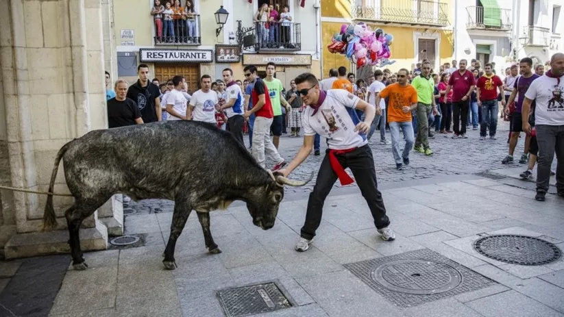 Joven frente a toro en calle concurrida