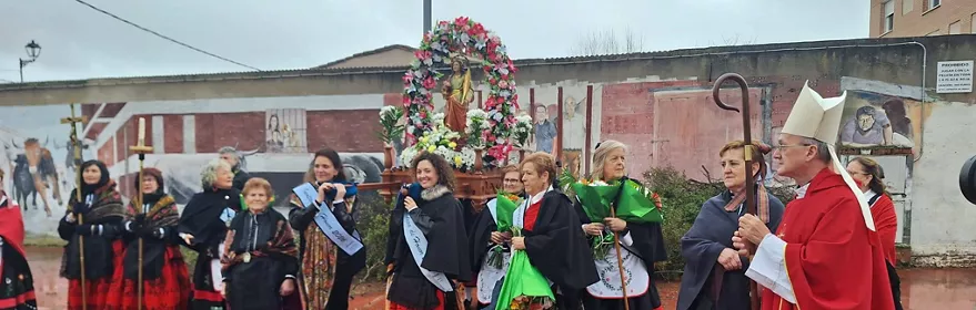 Procesión con imagen religiosa y trajes tradicionales bajo la lluvia.