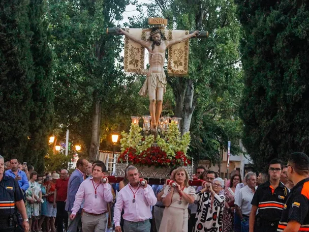 Paso procesional con imagen religiosa crucificada llevado a hombros entre una multitud.