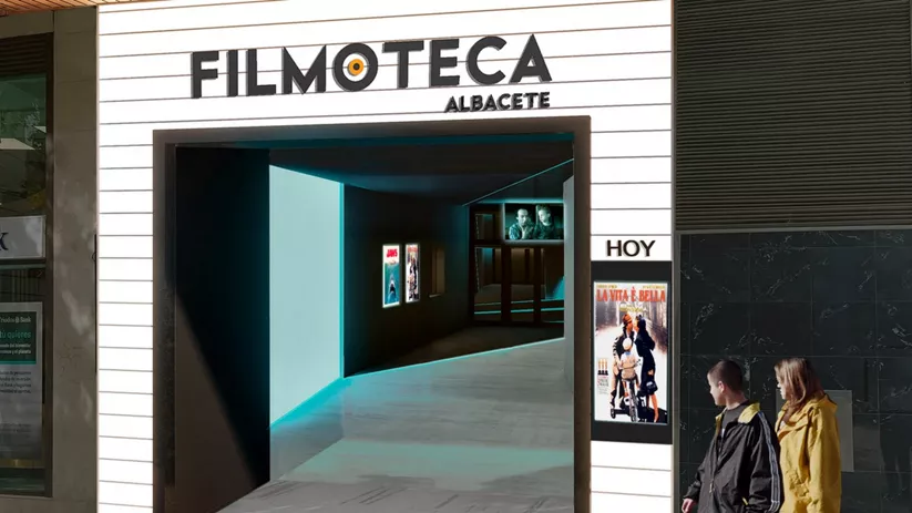 Entrada moderna a una sala de cine con cartelería iluminada y personas accediendo.