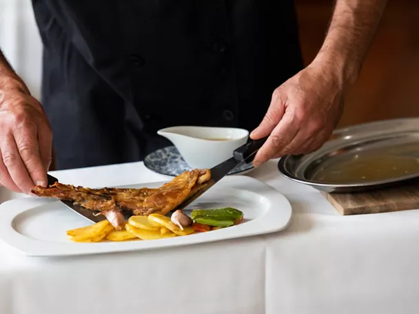 Chef sirviendo cordero asado con patatas