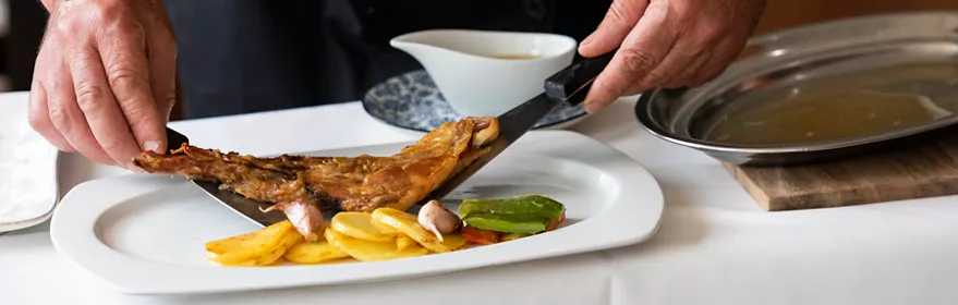 Chef sirviendo cordero asado con patatas