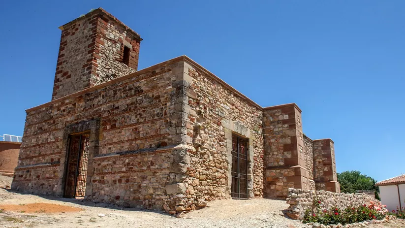 Fortaleza de piedra con torre cuadrada bajo un cielo despejado.