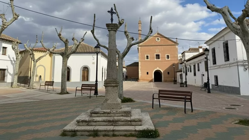 Plaza tranquila con crucero de piedra, bancos y ermita