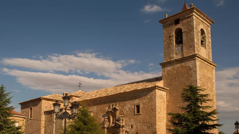 Fachada de iglesia con torre y plaza amplia