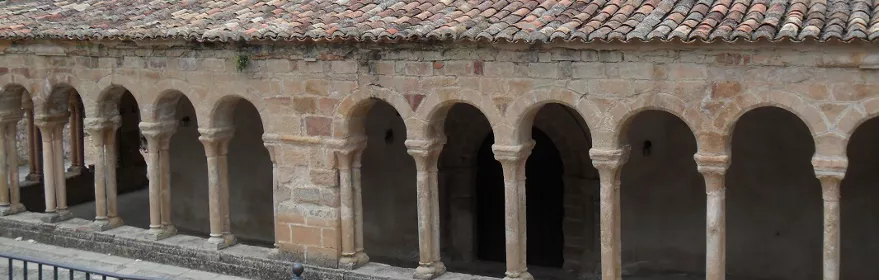 Galería porticada de piedra con arcos sobre columnas.