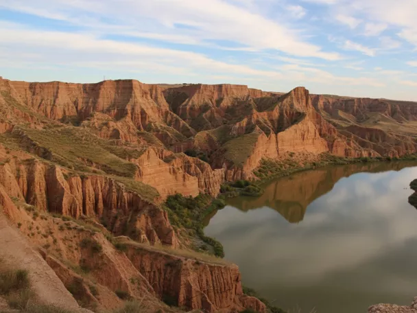 Barrancos rojizos junto a un río en paisaje erosionado