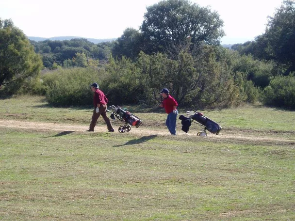 Jugadores caminando con carritos de golf