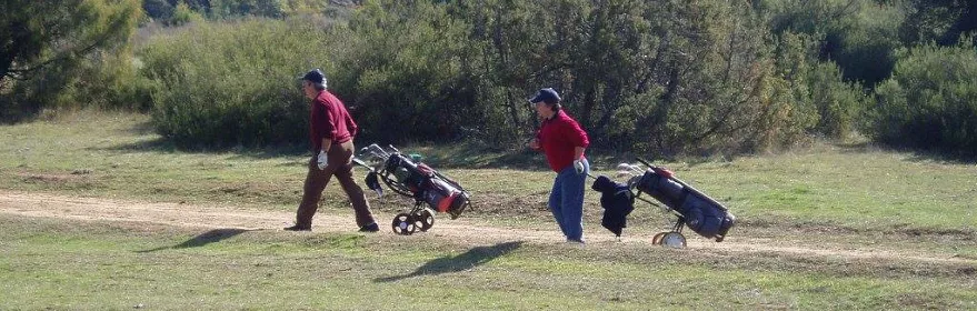 Jugadores caminando con carritos de golf