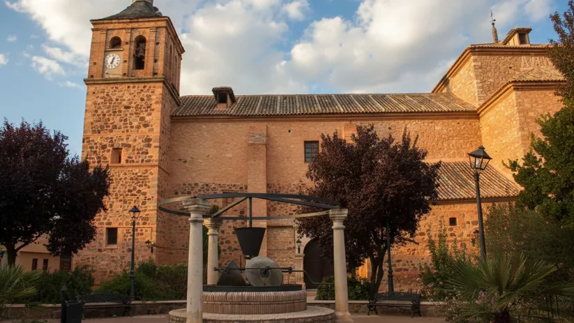 Iglesia parroquial de Granátula de Calatrava (Ciudad Real) con torre del reloj y plaza ajardinada.