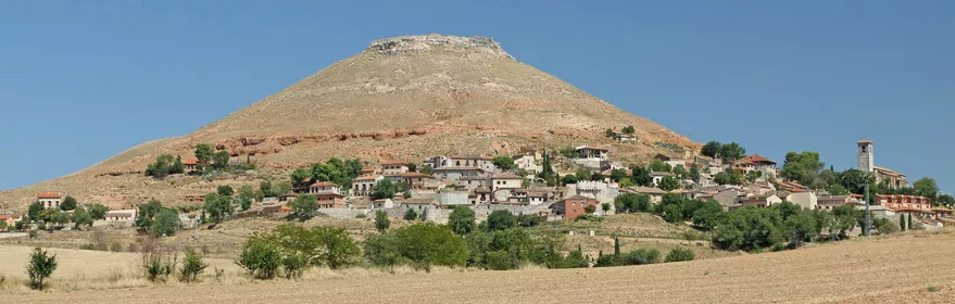 Pueblo en ladera con cerro al fondo y campos de cultivo.