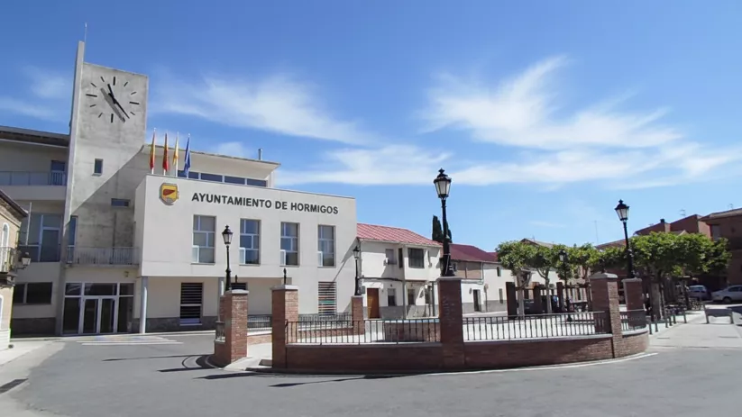 Ayuntamiento moderno junto a una plaza con farolas