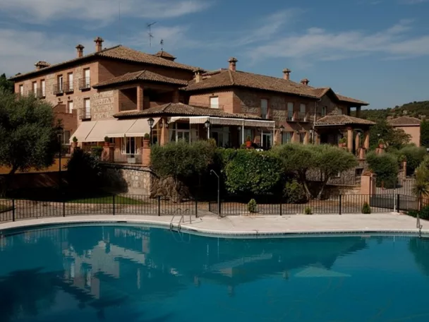 Edificio de estilo rústico con piscina exterior rodeada de vegetación.
