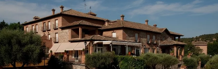 Edificio de estilo rústico con piscina exterior rodeada de vegetación.