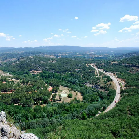 Valle verde con río y carretera.