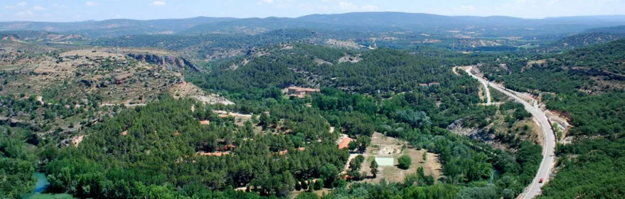 Valle verde con río y carretera.