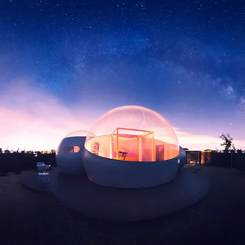 Cúpula transparente iluminada bajo un cielo nocturno lleno de estrellas.