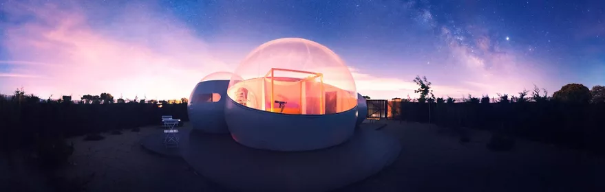 Cúpula transparente iluminada bajo un cielo nocturno lleno de estrellas.