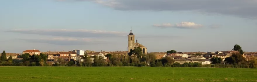 Panorámica del pueblo con campo verde y cielo nublado
