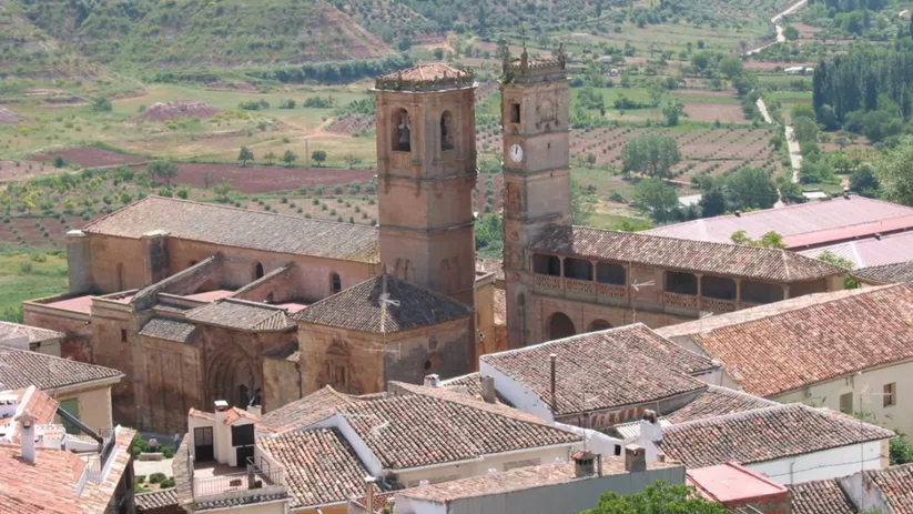 Vista panorámica del conjunto monumental con dos torres sobre un entorno rural.