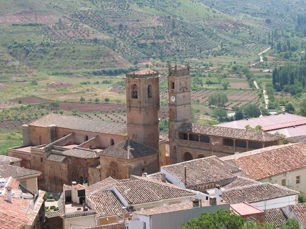 Vista panorámica del conjunto monumental con dos torres sobre un entorno rural.