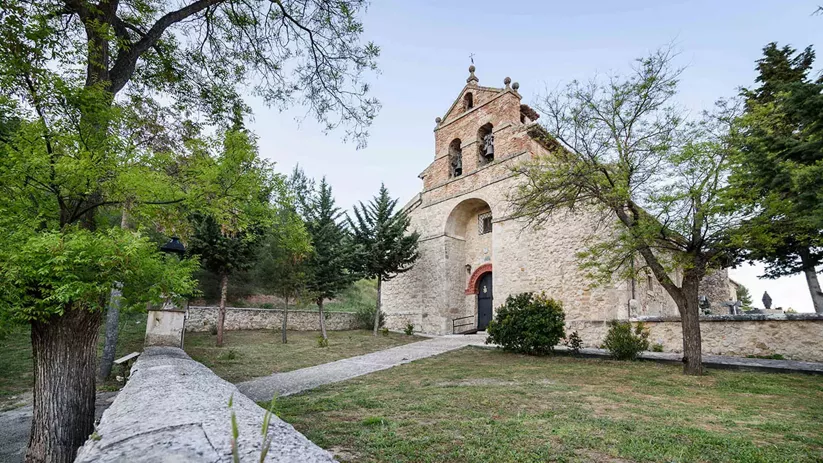 Iglesia de piedra junto a un camino entre árboles.