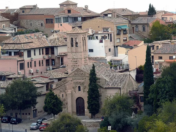 Vista elevada de iglesia de ladrillo entre casas con tejados de teja.