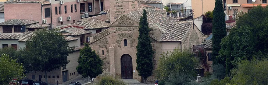 Vista elevada de iglesia de ladrillo entre casas con tejados de teja.