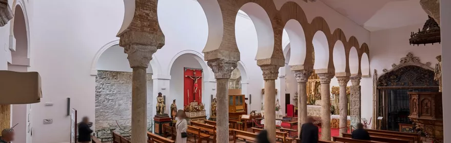 Nave con arcos de herradura y bancos de madera.