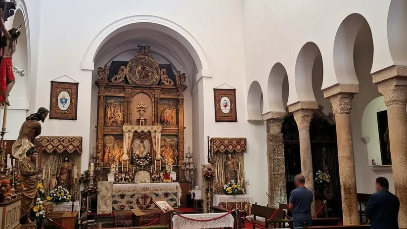 Interior de templo con retablo dorado y columnas de piedra.