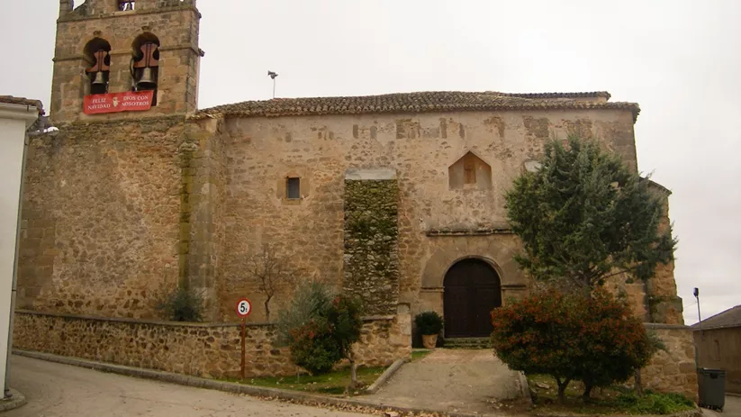 Iglesia de piedra con torre y fachada lateral.