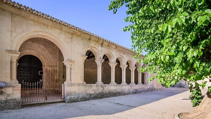 Galería porticada junto a calle arbolada.