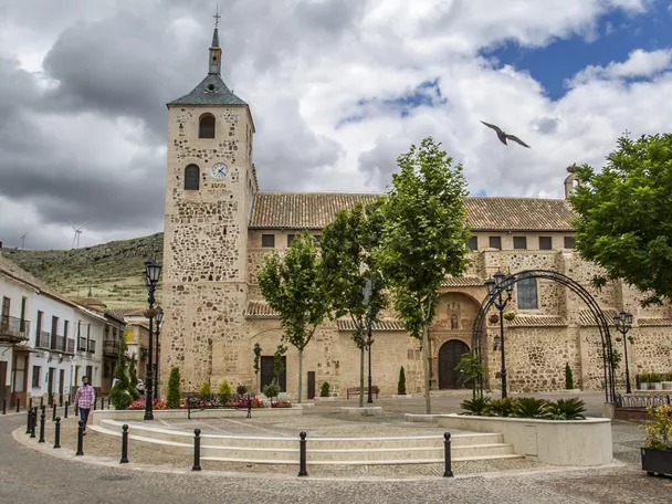 Plaza con iglesia de piedra y torre con reloj