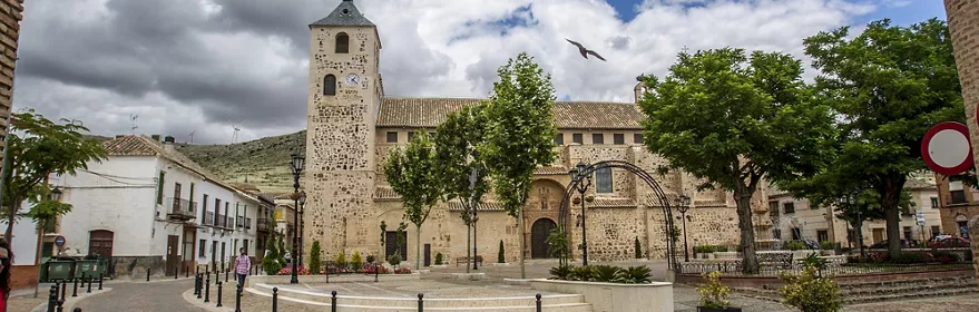 Plaza con iglesia de piedra y torre con reloj