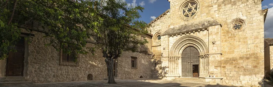 Plaza empedrada frente a iglesia románica de piedra.