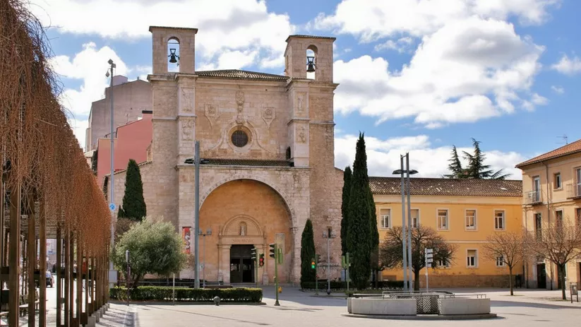 Plaza urbana con iglesia de piedra y torres campanario.