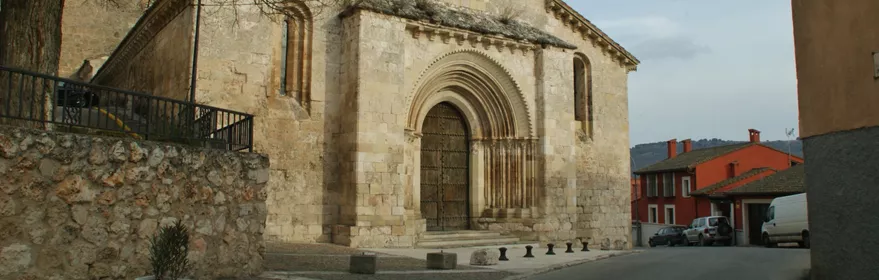Fachada románica de piedra junto a calle estrecha.