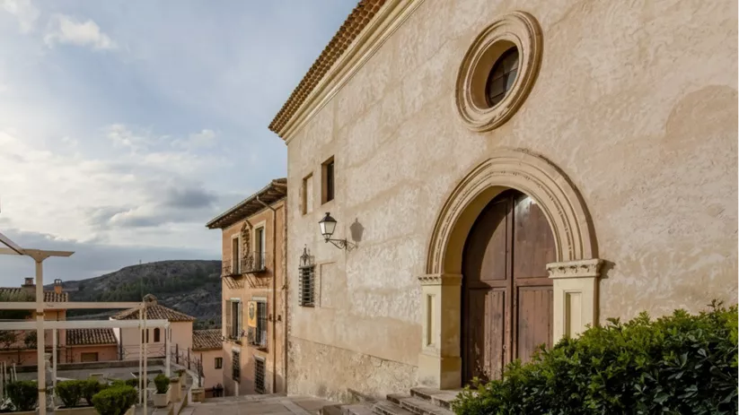 Entrada con arco de medio punto y escalinata en calle empedrada.