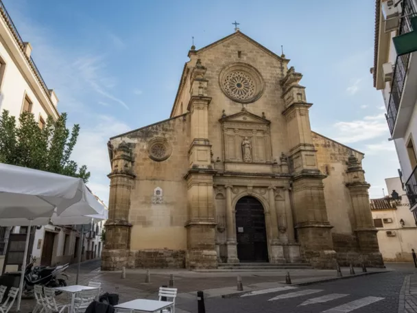 Iglesia de piedra vista desde una plaza con terraza exterior.