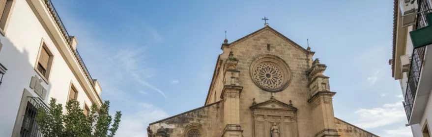 Iglesia de piedra vista desde una plaza con terraza exterior.