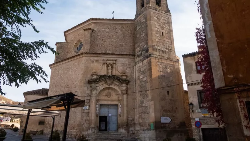 Fachada de iglesia de piedra con torre campanario.